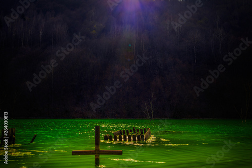 Fototapeta The remains of a graveyard located in a valley flooded with waste from a mining
