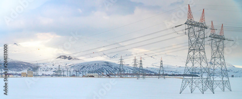 High voltage towers with blue sky and snowy landscape background