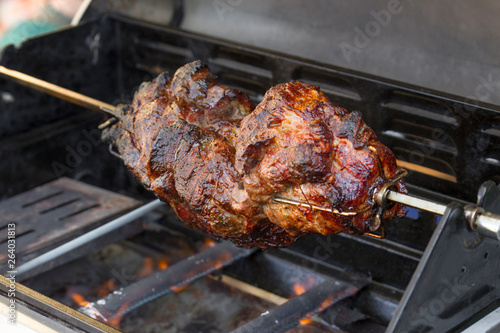 Crispy roast pork on a spit on a gas grill