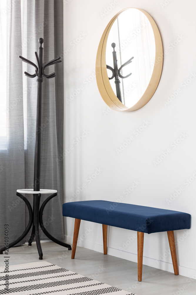 Coat hanger, blue settee and round mirror in wooden frame in spacious hall - obrazy, fototapety, plakaty 
