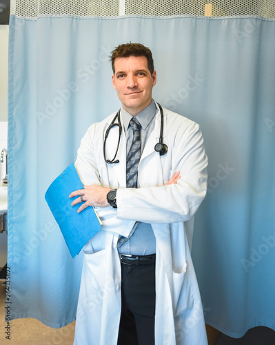 Doctor in white coat standing in front of hospital room curtain.