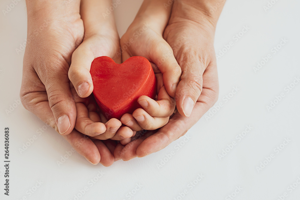 Obraz premium Woman and her child holding red heart in their hands on white background. Mother’s day background. International Heart Day concept.
