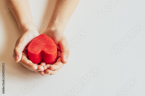 Fototapeta Naklejka Na Ścianę i Meble -  Child’s hands holding red heart on white background. Mother’s day background with copy space. International Heart Day concept.