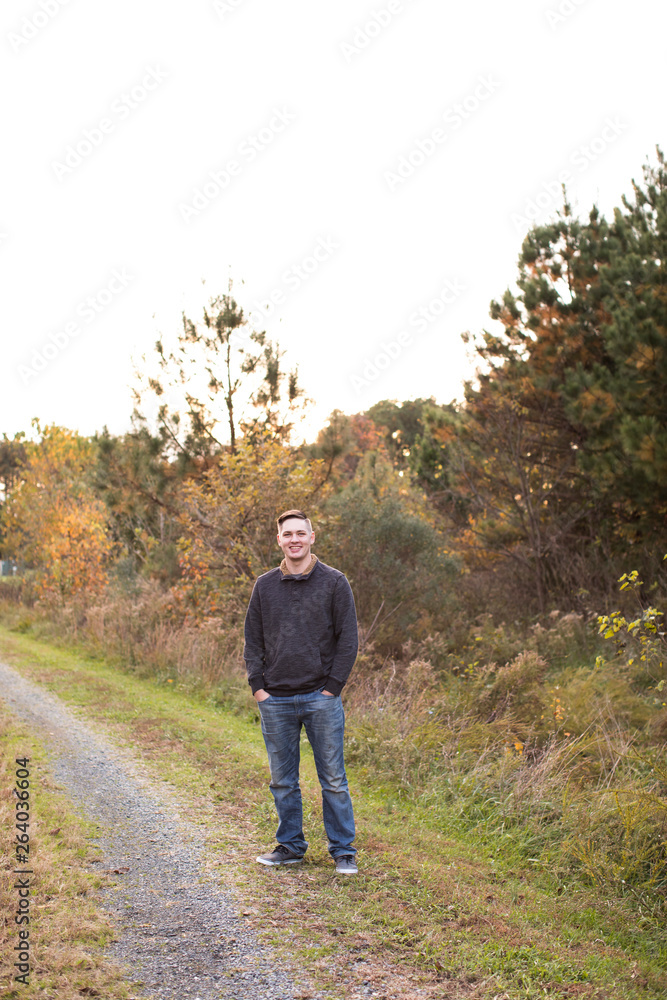 Wide View of Smiling 20 Year Old Man Standing on Trail at Sunset Wide View of Smiling 20 Year Old Man Standing on Trail at Sunset