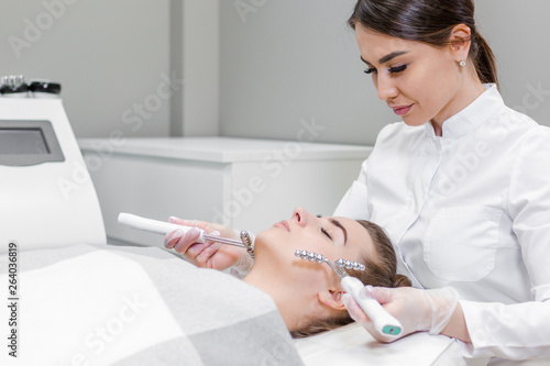 Beautician makes a therapeutic facial massage for a young girl