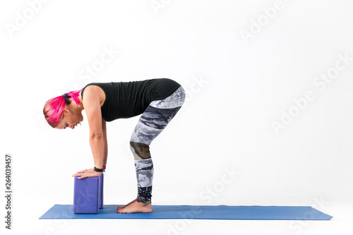 Young girl with bright hair doing fitness exercises on white background side view