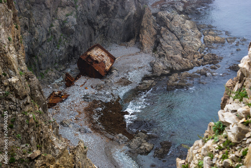 An old shipwrecked ship stands on the shore at the foot of a rocky cliff. Cape Briner. Primorsky Krai. Russia. photo