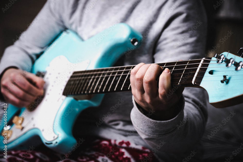Fototapeta premium Woman playing blue electric guitar close up at home. Practicing guitar