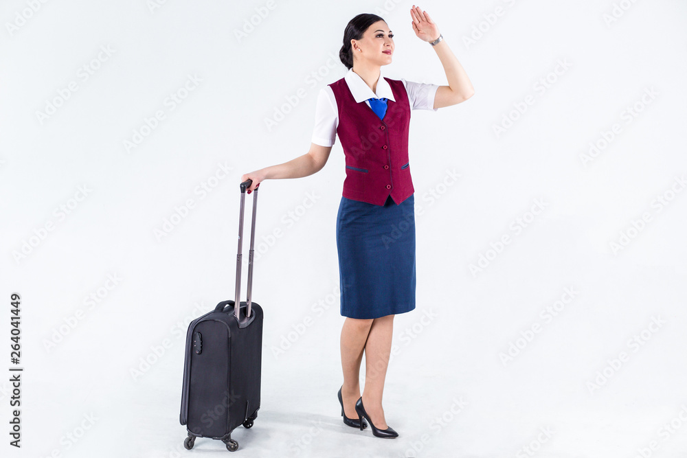 Woman stewardess holding a suitcase on a white background looking into the distance on a flying plane Woman stewardess holding a suitcase on a white background looking into the distance on a flying plane