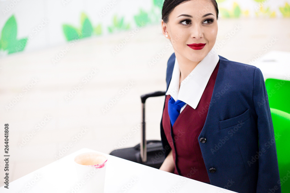 Flight attendant sitting at the table at the airport waiting for the departure of the aircraft Flight attendant sitting at the table at the airport waiting for the departure of the aircraft