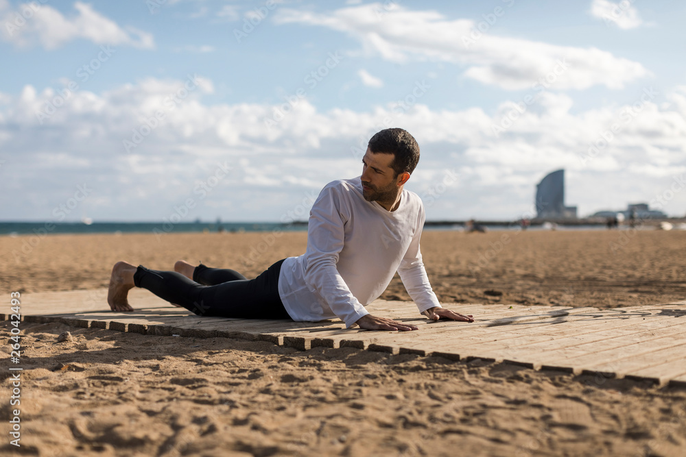 Man doing Yoga on the beach in Barcelona Man doing Yoga on the beach in Barcelona