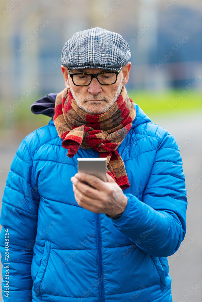 Confident senior man using smart phone, while standing outdoors Confident senior man using smart phone, while standing outdoors