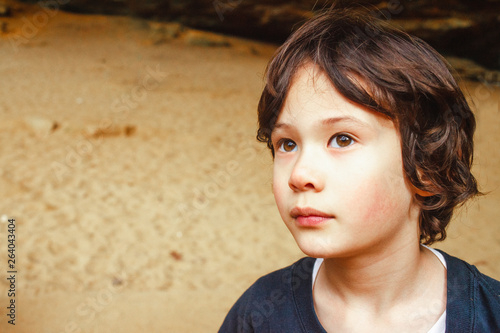 Portrait of a small boy standing outside in golden light looking up
