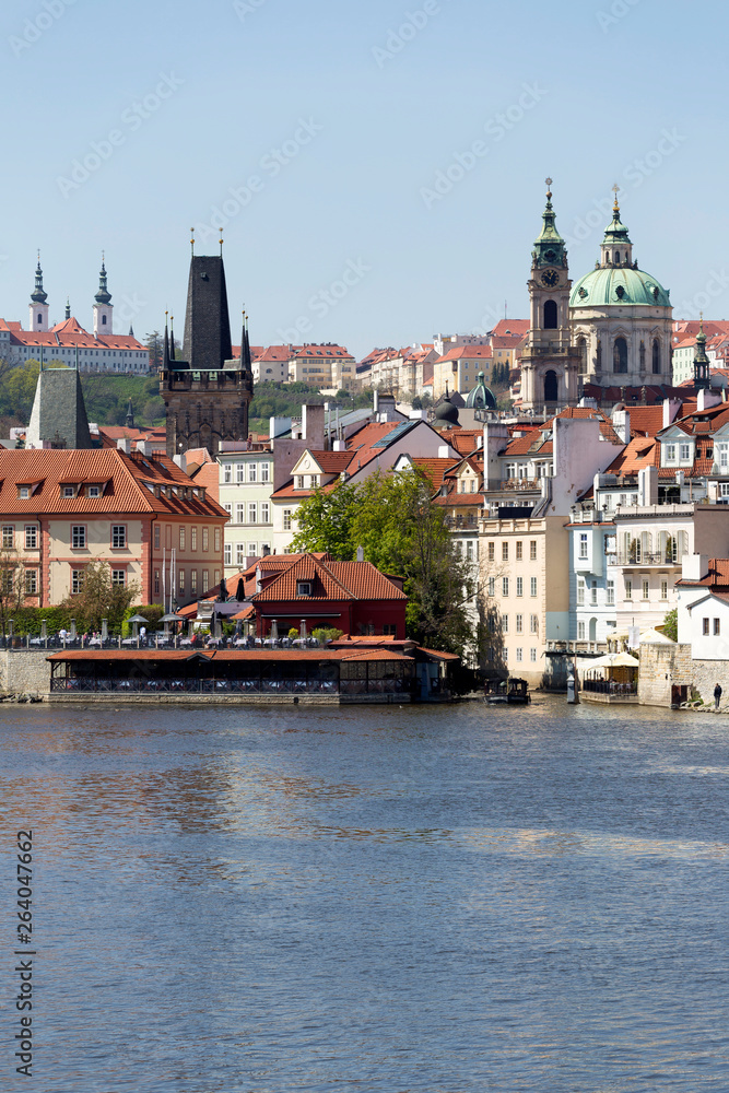 Obraz premium Spring green Prague baroque St. Nicholas' Cathedral with the Lesser Town above River Vltava in the sunny Day, Czech Republic