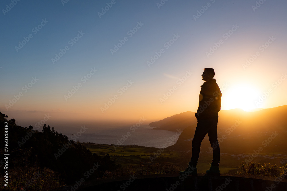 Man in beautiful inspiring sunrise with mountains and sea.