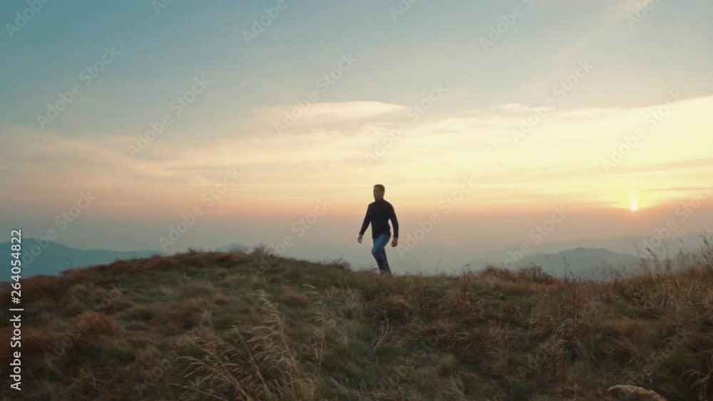 The male stands on mountain on a sunset background The male stands on mountain on a sunset background