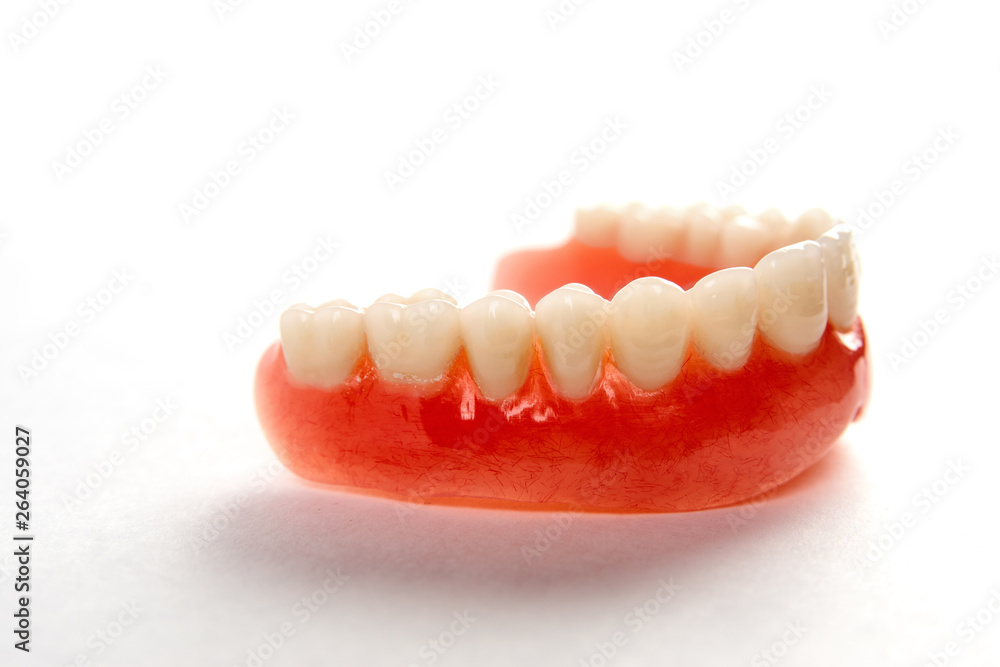 Obraz premium Artificial teeth on a white background with copy space, close-up
