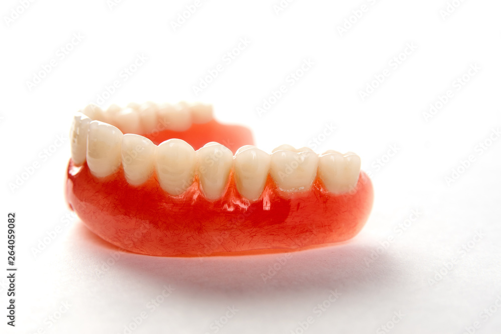 Obraz premium Artificial teeth on a white background with copy space, close-up