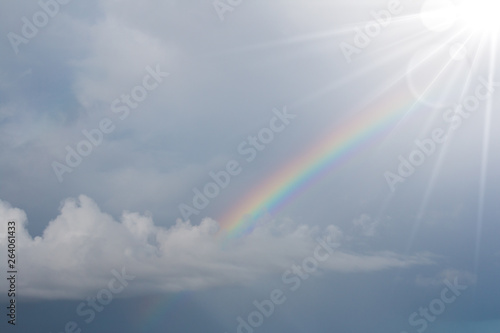 Rainbow in the blue sky with lighting flare