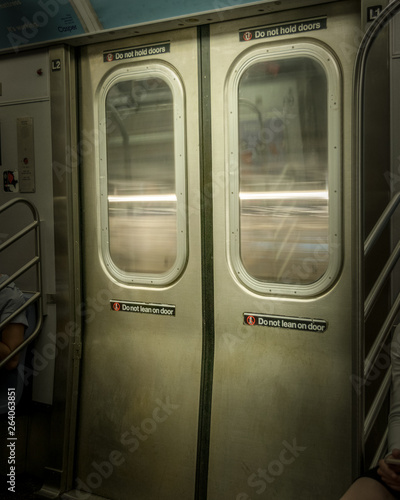 New York City Subway doors, closed, while train is moving, with light-streaks visible through the windows © Casual-T