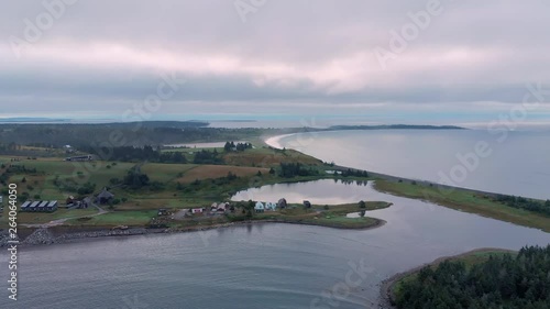 Cinematic drone / aerial footage moving forwards showing some farms, the ocean and a few chalets in Kingsburg, Nova Scotia, Canada during summer season. photo