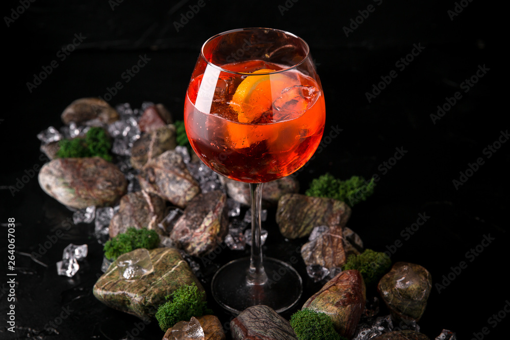 Aperol syringe soft alcoholic drink on a black background with stones and ice. Cocktail card for a bar or restaurant.