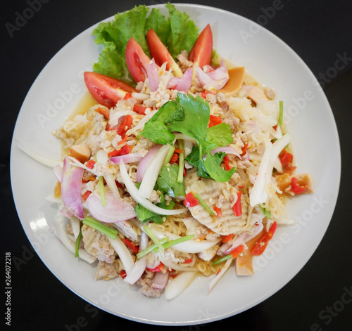 Instant noodle spicy salad food with herb pork and tomato vegetable celery mix on white plate top view