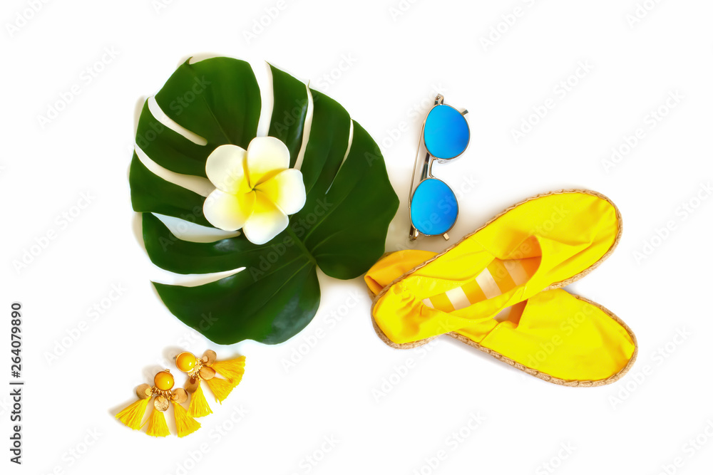 Obraz premium Creative layout made of summer feminine accessories, green Tropical leaf Monstera, sunglasses, espadrilles and bright earrings on a white background. Vacation concept. Travel flat lay, top view.