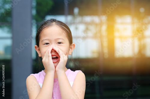 Portrait little Asian child girl acting and shouting through hands like megaphone. Communication concept.