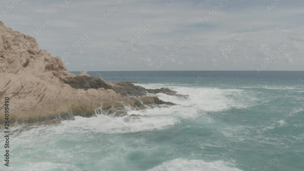 Zoom out view of a jagged rocks being hit by the waves Zoom out view of a jagged rocks being hit by the waves