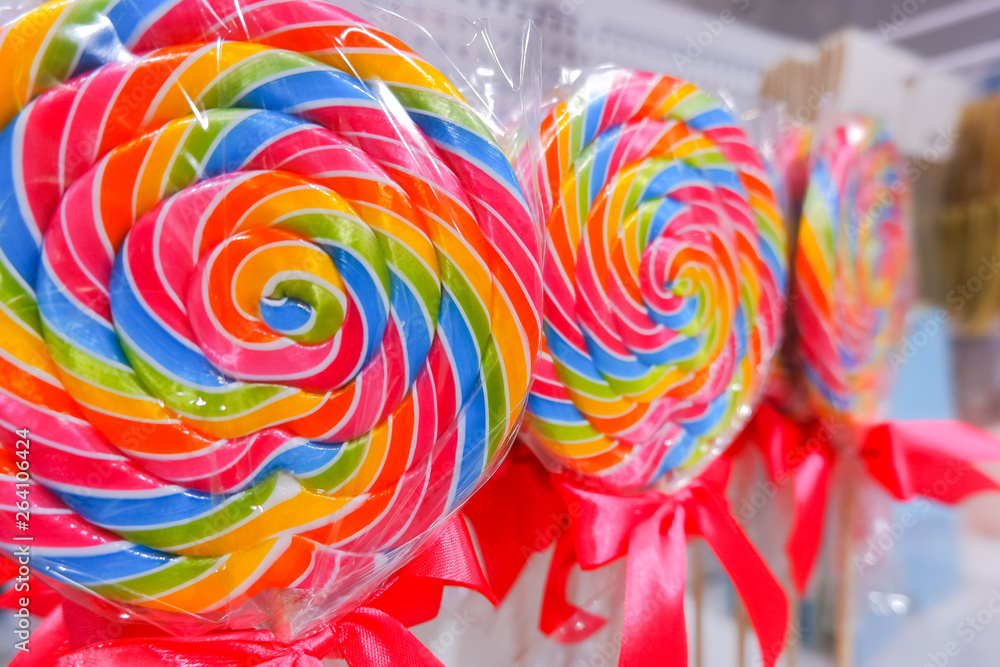 Rainbow lollipop swirl on wooden stick in candy store,Selective focus.sweet candy.Candy bar.Lollipops close up on sale in street market.