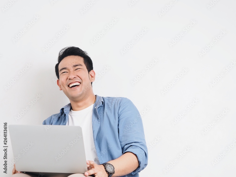 Happy Asian man using laptop at home.