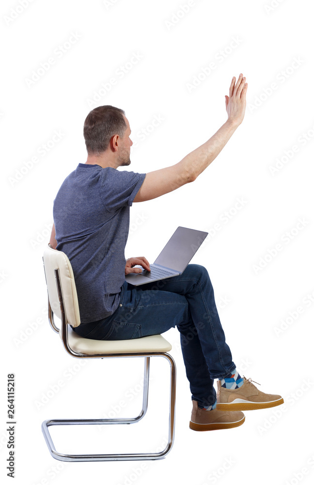 Side view of a man who sits on a chair with a laptop and points Side view of a man who sits on a chair with a laptop and points