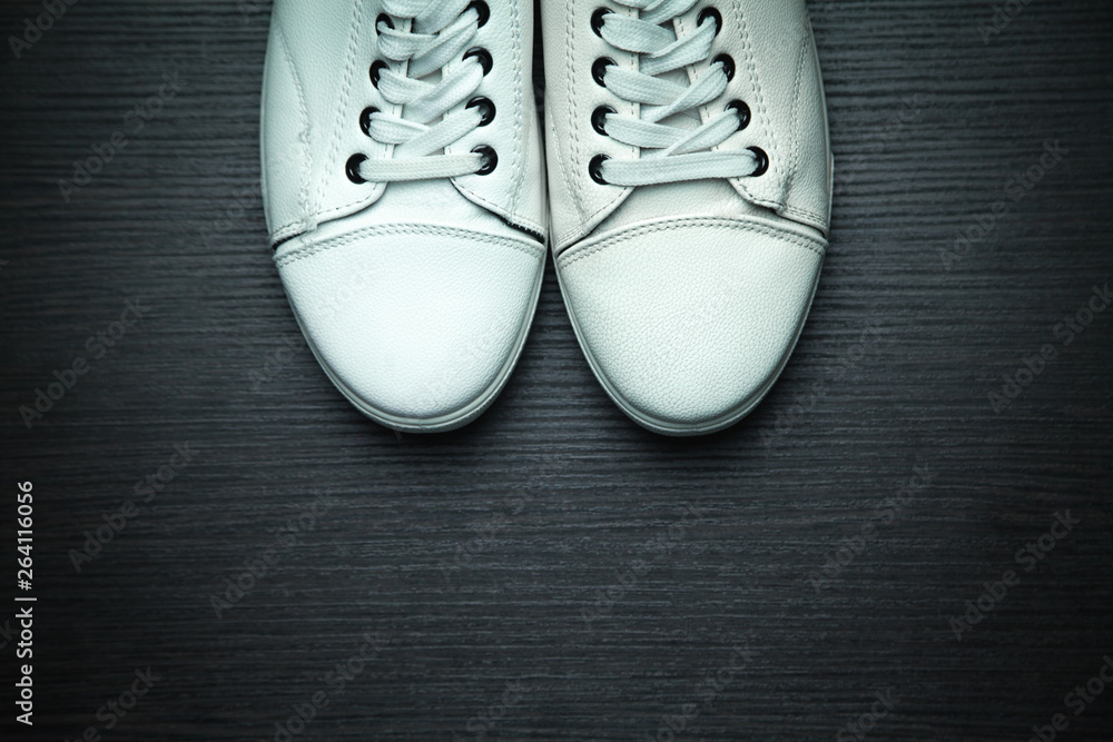 White sneakers on a black wooden background.