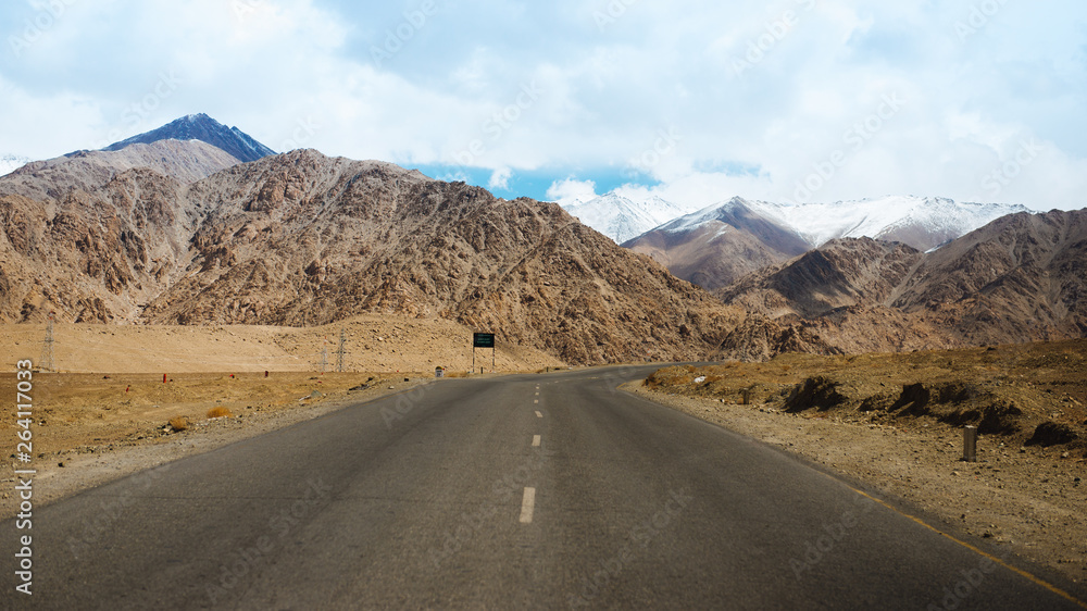 Straight road leading towards a snow capped mountain in leh, ladakh, india.