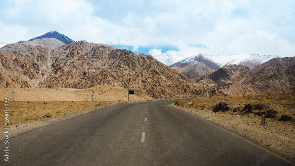 Straight road leading towards a snow capped mountain in leh, ladakh, india. Straight road leading towards a snow capped mountain in leh, ladakh, india.