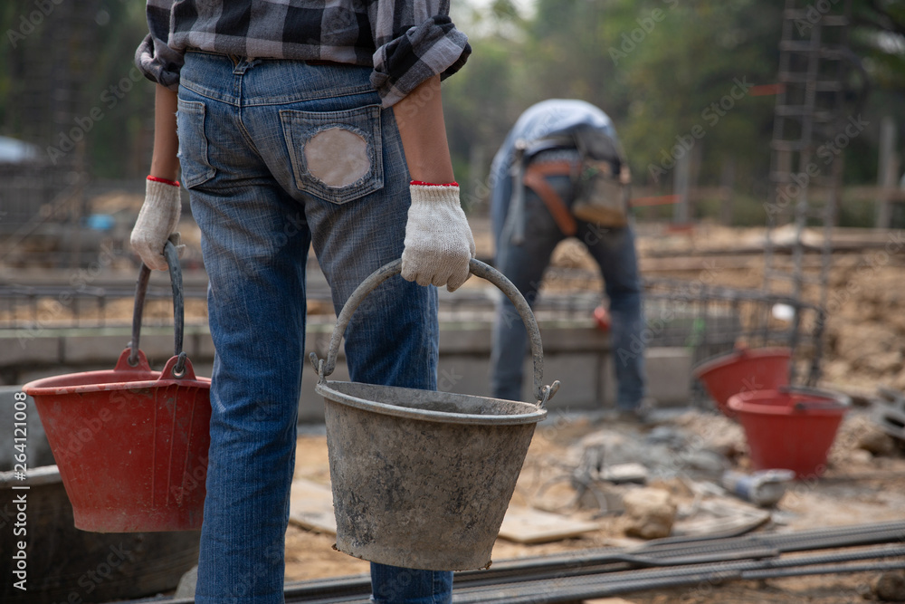 Construction worker holding a bucket of wet concrete Construction worker holding a bucket of wet concrete