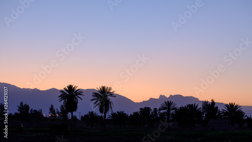 Silhouttes of trees, Shafiabad and mountains during sunset, Kalut Shahdad Desert