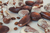 Chocolate candies in the shape of shells lie on the table. Chocolate shells of different shapes.