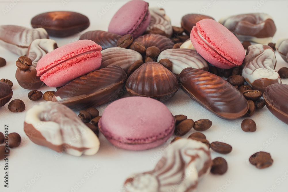 Macaroons, coffee beans and chocolate shells on a white background. Sweets and coffee on a white background Macaroons, coffee beans and chocolate shells on a white background. Sweets and coffee on a white background