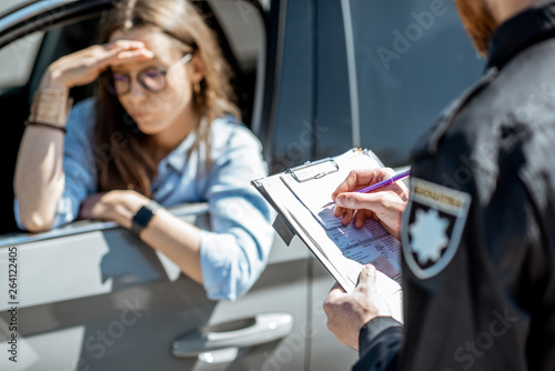 Policeman issuing a fine for violating the traffic rules to a young woman driver photo