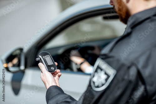 Bild auf Leinwand Policeman holding device for checking alcohol intoxication while standing near t