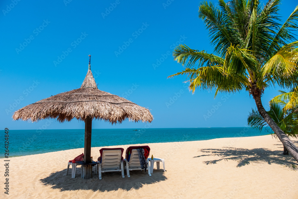 Couple beach chairs and coconut plam tree on tropical beach with sea and blue sky background. Summer background concept.