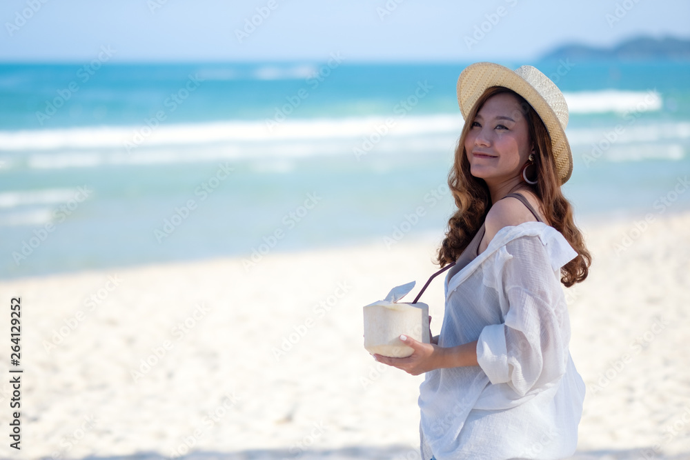 Portrait image of a beautiful asian woman holding and drinking coconut juice on the beach