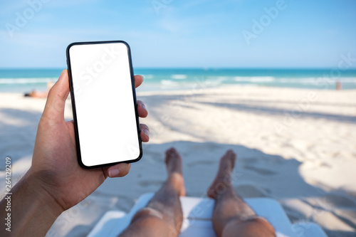 Download Mockup Image Of A Man S Hand Holding White Mobile Phone With Blank Desktop Screen While Laying Down On Beach Chair Stock Photo Adobe Stock