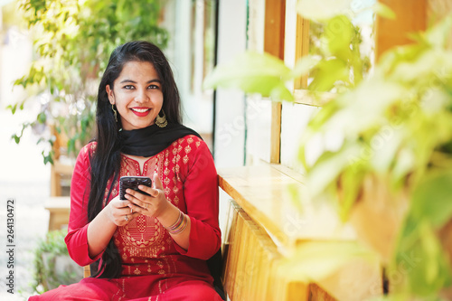 Pretty young indian woman using her phone and looking at camera