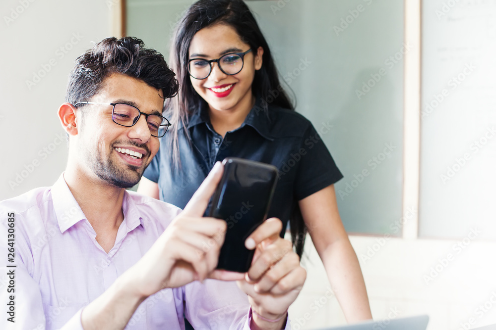 Handsome indian man using his phone and showing it to beautiful indian young woman Handsome indian man using his phone and showing it to beautiful indian young woman