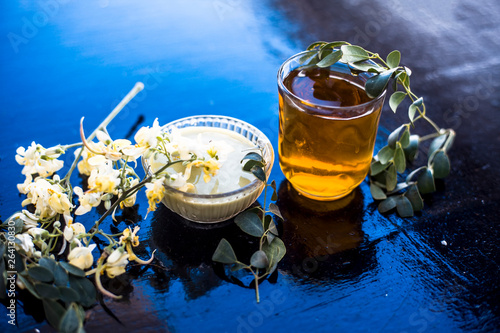 Bunch of flowers of drumstick on wooden surface along with its extracted water or tincture in a glass. photo