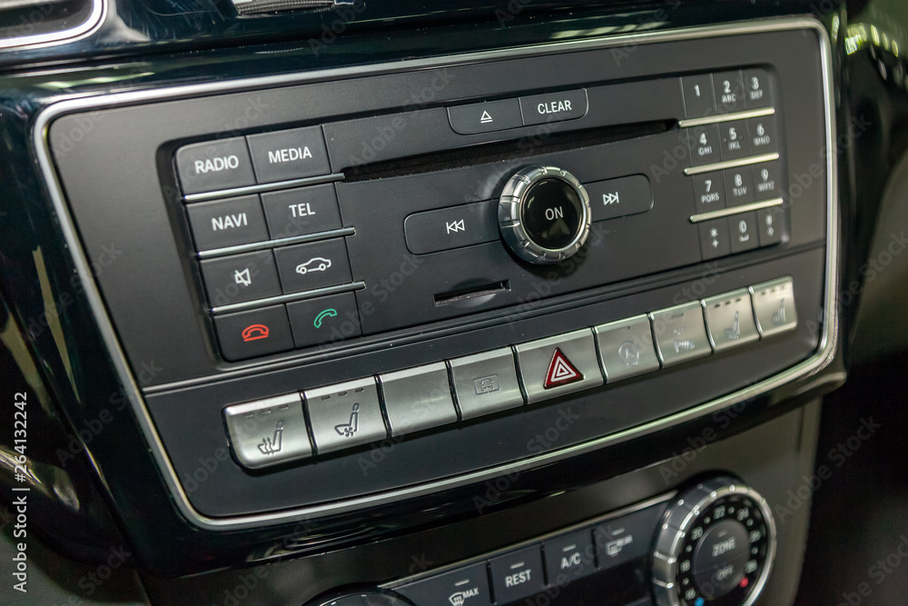 The control panel of the multimedia system, radio, telephone, heated seats and ventilation, emergency stop button and a hole for the memory card on the dashboard of black plastic and chrome luxury car The control panel of the multimedia system, radio, telephone, heated seats and ventilation, emergency stop button and a hole for the memory card on the dashboard of black plastic and chrome luxury car