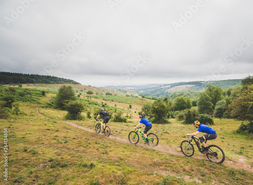Friends enjoy riding mountain bikes in English countryside